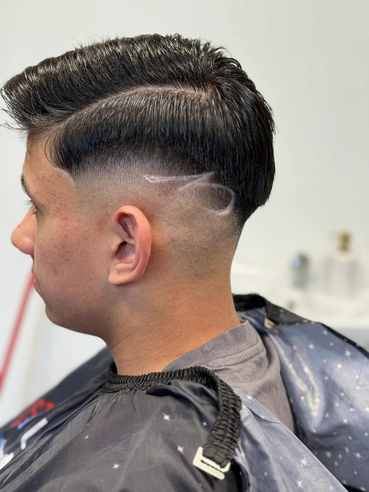 Tmavý slick back s skin fade a zahnutým vzorem
