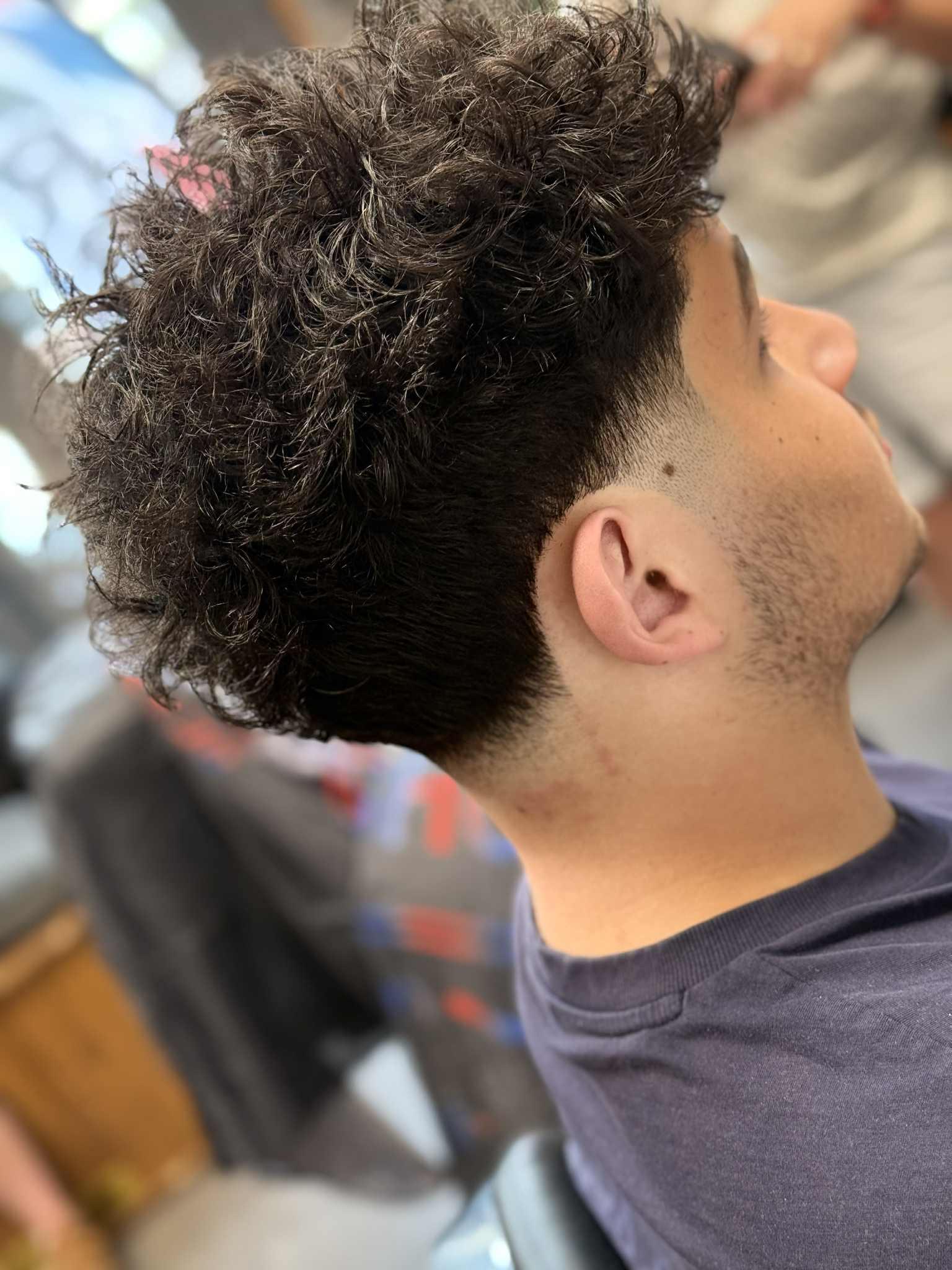 Kudrnaté tmavé vlasy s low fade a strništěm